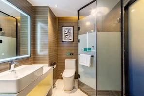 Un bany modern amb un mirall gran, un lavabo, un vàter i una cabina de dutxa de vidre.