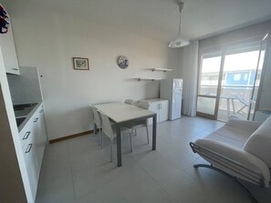A modern, well-lit room with a dining table, chairs, a sofa, and a refrigerator. - Seaside Comfort Accommodation Near the sea (San Michele al Tagliamento)
