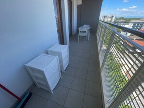 A balcony with a tiled floor, white plastic storage units, and a metal railing. - Seaside Comfort Accommodation Near the sea (San Michele al Tagliamento)