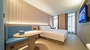 Een hotelkamer met een bed, een zithoek, een televisie en een wandgemonteerd scherm.