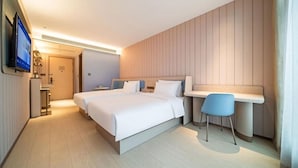 Een moderne hotelkamer met een groot bed, nachtkastjes, een bureau met stoel, een televisie en een badkamer in de achtergrond.