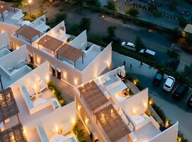 Un hotel moderno con varias edificaciones blancas, cada una con techo plano y zonas de estar al aire libre.