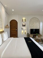Una habitación de hotel con cama, televisión, escritorio y pared de piedra.