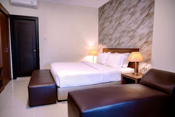 Una habitación de hotel con una cama, dos mesitas de noche y una zona de estar.