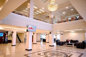 A spacious lobby with a chandelier, a sign for 'SMART', and a staircase leading to an upper level. - Smart Hotel (Lubuklinggau)