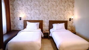 A hotel room with two single beds, a nightstand between them, and a patterned wallpaper. - Smart Hotel (Lubuklinggau)