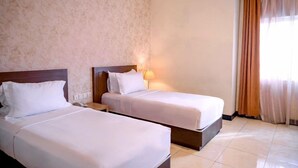 A hotel room with two beds, a nightstand, a lamp, and a window with curtains. - Smart Hotel (Lubuklinggau)