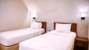 Et hotelværelse med to enkeltsenge, et træhovedgærde, et natbord og en lampe på væggen.