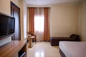 Habitación de hotel con televisor de pantalla plana, escritorio, silla, sofá y cama.