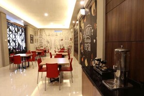 A restaurant with tables and chairs, a counter with a coffee machine, and a wall with a mural.