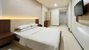 Een hotelkamer met een bed, nachtkastje en een aan de muur bevestigde flatscreen-televisie.