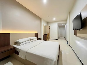 Habitació d'hotel amb llit, taula de nit i televisió de pantalla plana penjada a la paret.