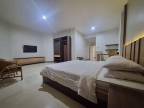 A hotel room with a large bed, a TV, a wardrobe, and a seating area. - Mycity Hotel (Tarakan)