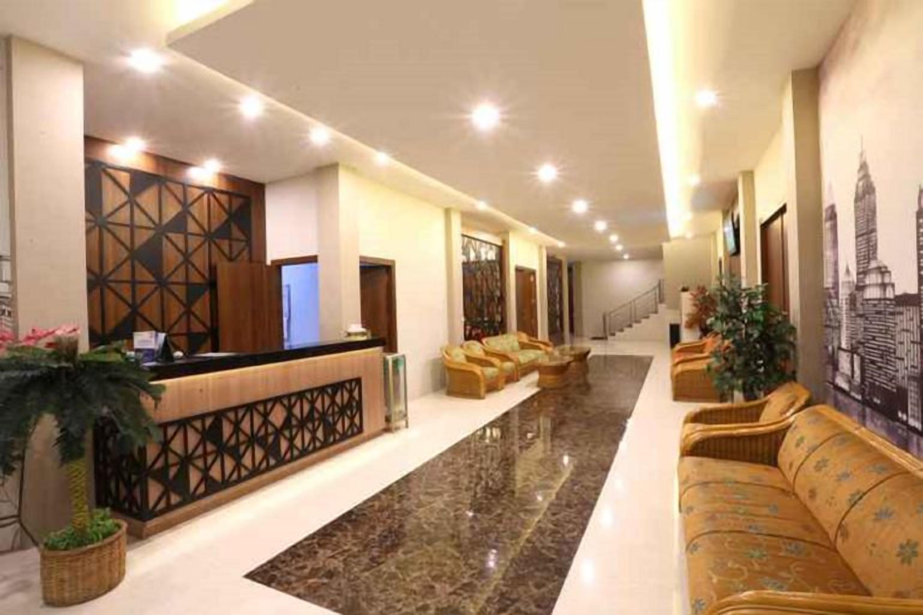A hotel lobby with a reception desk, seating area, and a staircase.