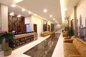Un vestíbulo de hotel con mostrador de recepción, zona de estar y una escalera.