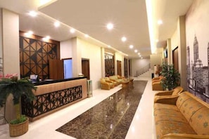 A hotel lobby with a reception desk, seating area, and a staircase. - Mycity Hotel (Tarakan)