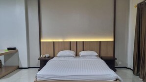 Een moderne hotelkamer met een groot bed, nachtkastjes en een hoofdeinde met ingebouwde verlichting.