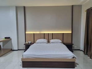 Habitació d'hotel moderna amb un llit gran, taules de nit i un capçal de llit amb il·luminació integrada.