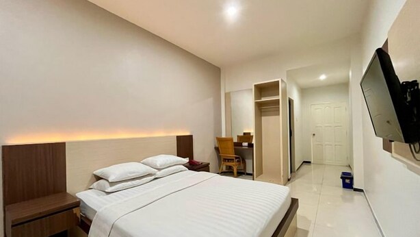 Een hotelkamer met een bed, nachtkastje en een aan de muur bevestigde televisie.