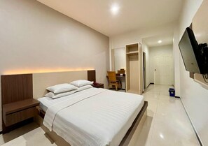 Ein Hotelzimmer mit einem Bett, einem Nachttisch und einem an der Wand befestigten Fernseher.