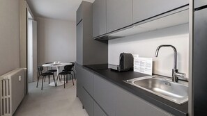 Una cocina moderna con un lavamanos de acero inoxidable, una cafetera y un comedor con mesa y sillas.