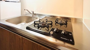 A modern kitchen with a stainless steel gas stove, a sink, and wooden cabinets. - Hotel Arashi Nambaminami No003 (Osaka)