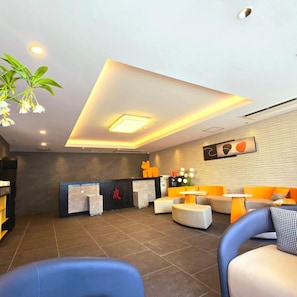 Una zona d'estació moderna amb taulell de recepció, espai per seure i una paret decorativa.