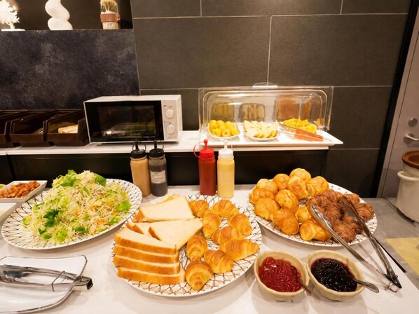Buffet amb diferents plats, com ara sandvitxos, croissants i amanida.