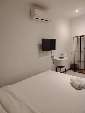 Habitación de hotel con una cama, un televisor montado en la pared y un escritorio con una silla.