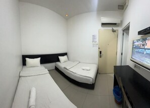 Una habitación de hotel con dos camas individuales, televisión, puerta y aire acondicionado.