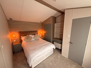 A bedroom with a bed, bedside tables, a wardrobe, and a door.