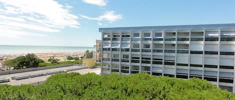 A modern building with multiple balconies overlooking a beach.