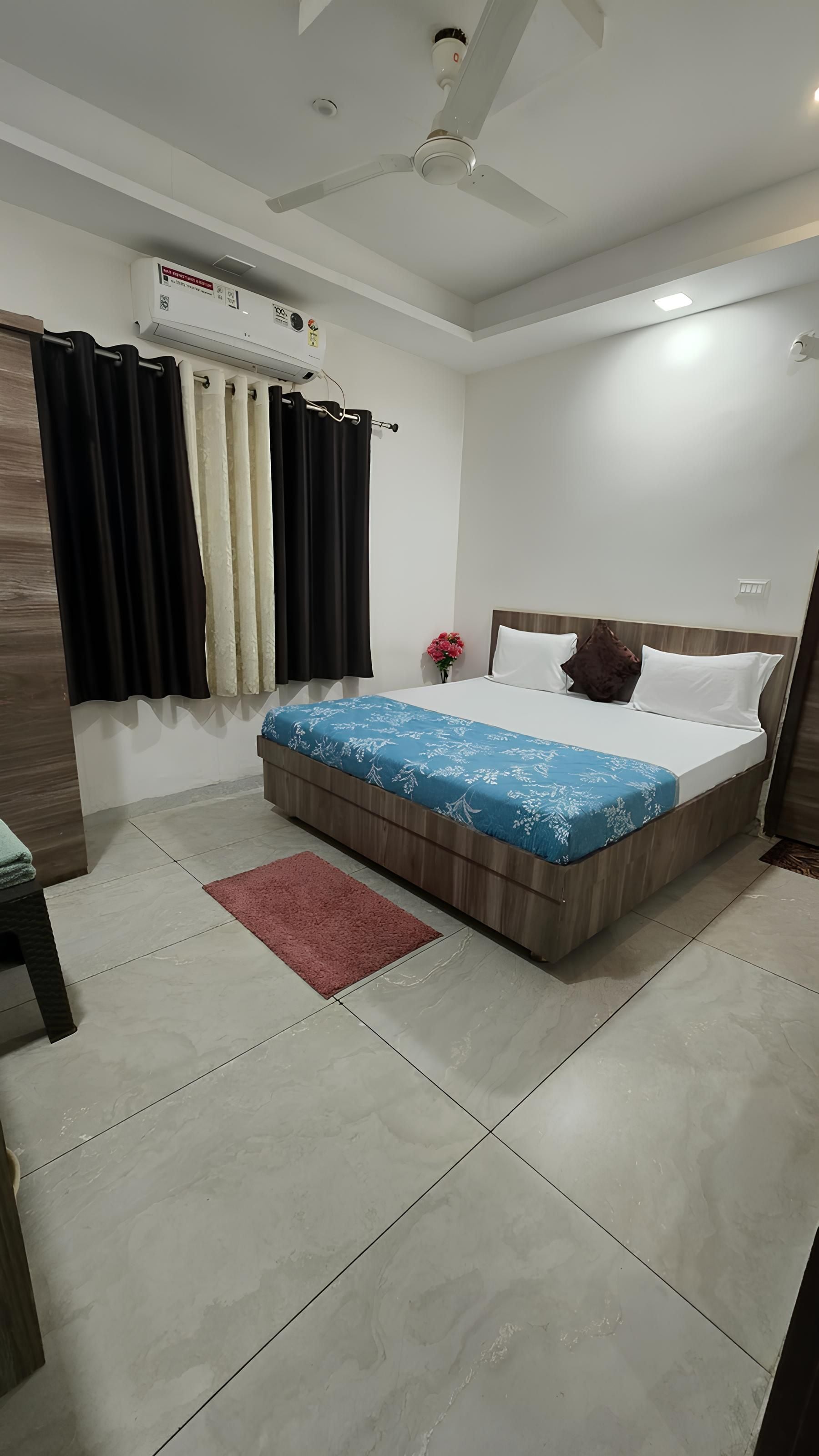 A bedroom with a bed, a ceiling fan, an air conditioning unit, and a red rug.