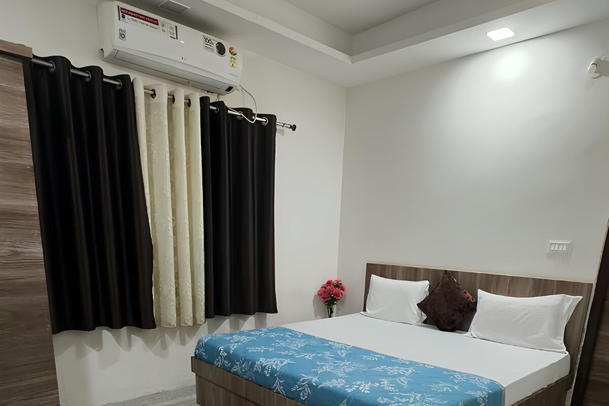 A bedroom with a bed, a ceiling fan, an air conditioning unit, and a red rug.