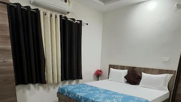 A bedroom with a bed, a ceiling fan, an air conditioning unit, and a red rug.