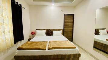 A hotel room with a bed, a mirror, a door, and a curtain.