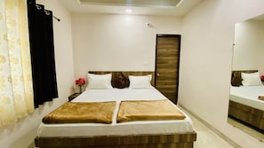 A hotel room with a bed, a mirror, a door, and a curtain. - Mandu Green Villa  (Mandav)