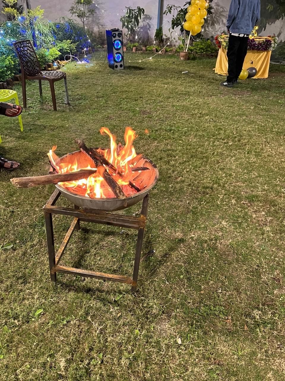 Un hogar a prueba de fuego de metal con leña encendida sobre un césped.