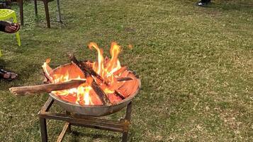 Un hogar a prueba de fuego de metal con leña encendida sobre un césped.