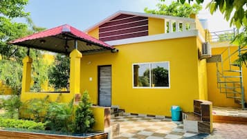 A yellow building with a red roof, a window, and a door.