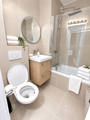 Une salle de bain moderne équipée de toilettes, d’un lavabo, d’un miroir et d’une douche.