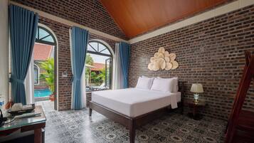 A bedroom with a large bed, a brick wall, and a view of a swimming pool.