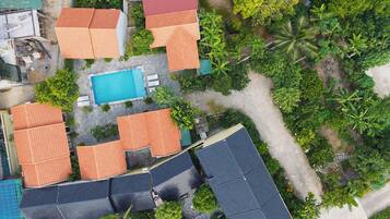 Vista aérea de um bairro residencial com várias casas, piscina e vegetação ao redor.