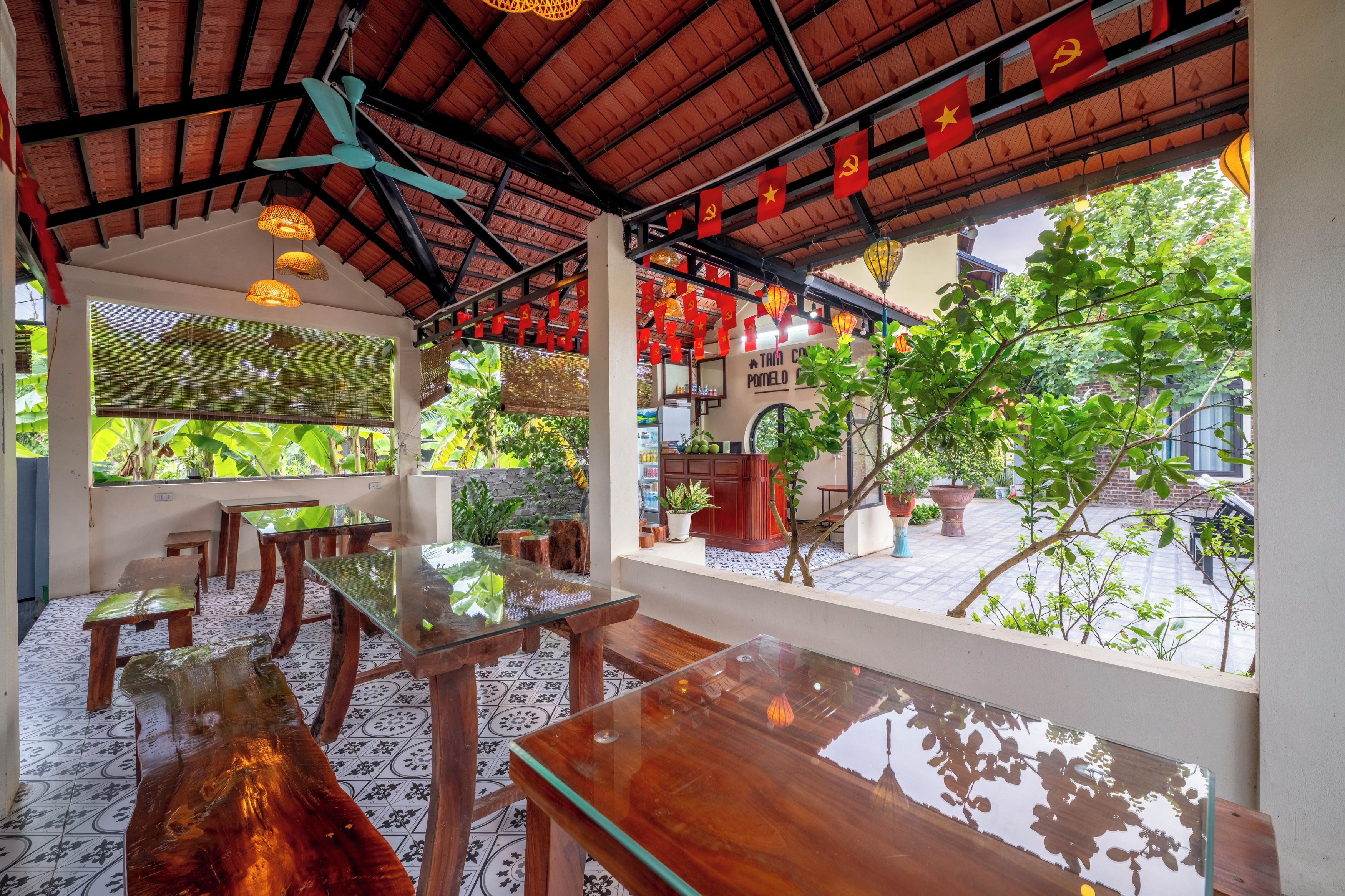 A restaurant with wooden tables and chairs, a tiled floor, and a view of greenery outside.