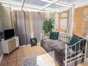 A room with a bed, a TV on a cabinet, a small table, and a potted plant. - Cosy Escape (Birmingham)