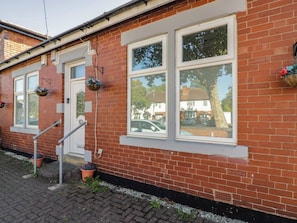 A red brick building with white-framed windows, a door, and a small step leading to the entrance. - Cosy Escape (Birmingham)