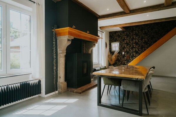 A dining area with a table and chairs, a fireplace, and a staircase.