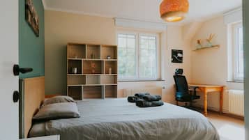 Une chambre à coucher comprenant un lit, un bureau, une chaise, une étagère et une fenêtre.