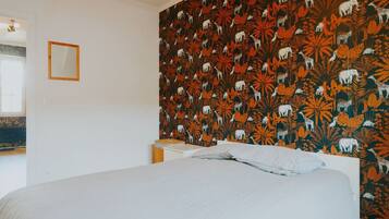 Een slaapkamer met een bed, een nachtkastje en een wand met behangpapier met een patroon.