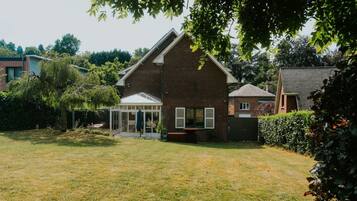 A residential property with a brick house, a conservatory, and a well-maintained lawn.